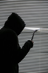 Criminal with crowbar is spying through the window. Old shutter blinds.