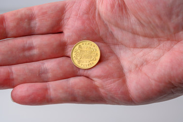Spanish gold one (una)peseta coin reverse side change in the hand from shopping