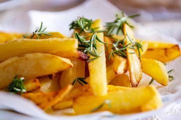 Golden fried potatoes chips  with fresh aromatic rosemary herb
