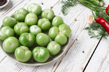 green tomatoes,pickles background on white wooden table with green and red and chilli peppers,fennel,salt,black peppercorns,garlic,pea,close up,healthy concept,top view,flat lay