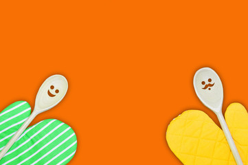 Home cooking concept with funny spoons and kitchen potholder, top view