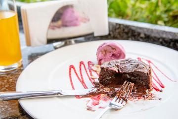 Warm dessert chocolate cake Fondant on plate with ice-cream ball, mint, icing on the table in a summer cafe under an open sky. Chocolate lava cake with ice cream