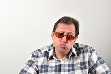 Portrait of a mature man in glasses, a plaid shirt on a white background. Emotions and gestures.