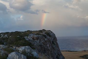 Fototapeta na wymiar Rainbow over rocks in Cape Greco, Cyprus