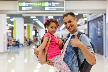 Daddy is embracing girl in the airport hall with happiness.