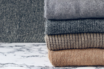 stack of cozy knitted sweaters on wooden background. Autumn-winter concept,Knitted wool sweaters. Pile of knitted winter clothes on marble background, sweaters, knitwear, space for text