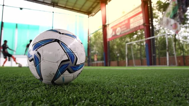 4K Footballer doing training and kicks ups as a soccer ball is in the foreground