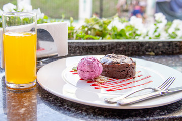 Warm dessert chocolate cake Fondant on plate with ice-cream ball, mint, icing on the table in a summer cafe under an open sky. Chocolate lava cake with ice cream