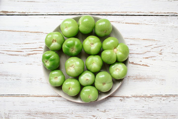 green tomatoes,pickles background on white wooden table with green and red and chilli peppers,fennel,salt,black peppercorns,garlic,pea,close up,healthy concept,top view,flat lay