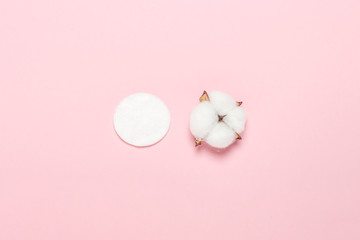 Cotton hygienic make-up disk and cotton flower on a pink background. Makeup and hygiene concept, natural product. Flat lay, top view