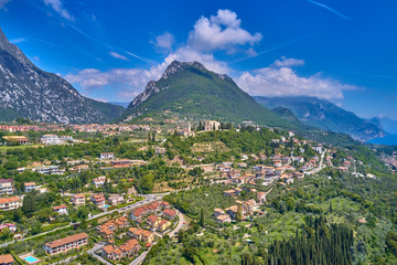 Fototapeta na wymiar The resort town of Pulciano, located on the shores of Lake Garda. San Michele Arcangelo Church is located on a mountain. Panoramic view of the city, church, Lake Garda, Alps. Aerial view.