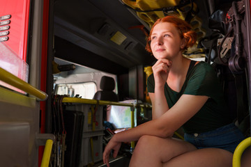 Photo of ginger girl looking to side sitting in cab of fire engine