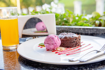 Warm dessert chocolate cake Fondant on plate with ice-cream ball, mint, icing on the table in a summer cafe under an open sky. Chocolate lava cake with ice cream