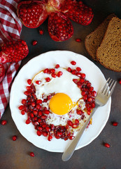 Traditional Azerbaijan cuisine pomegranate with egg narnumru on white plate on black background,top view,close-up