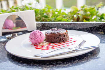 Warm dessert chocolate cake Fondant on plate with ice-cream ball, mint, icing on the table in a summer cafe under an open sky. Chocolate lava cake with ice cream