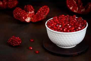 Pomegranate seeds in a bowl on black background.