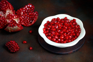 Pomegranate seeds in a bowl on black background.