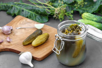 Pickles - canned fermented cucumbers in glass jar on dark background, horizontal orientation