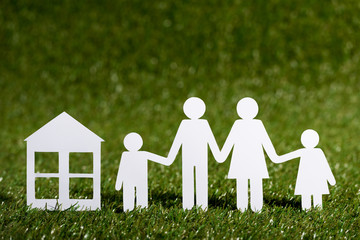 Paper cut of family near house on the artificial grass