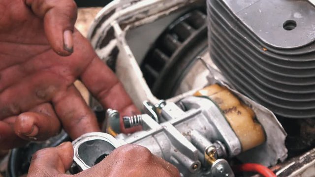 Close Shot of Hands Working on a Chainsaw Engine