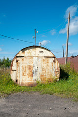 The cylindrical building is industrial. The building is made in the form of a tube and is used for parking a car. Iron and round garage