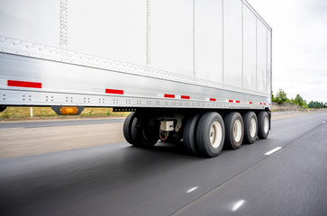 Fototapeta na wymiar Big rig semi truck transports a heavy-duty four-axle semi trailer running on the highway