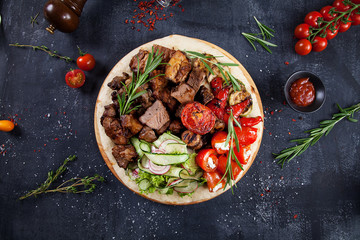 Close up view on tasty grilled meat with vegetables on georgian pita. shashlik or barbecue meat on...