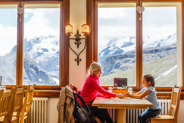 Mother and little daughter at the restaurant in the mountains with beautiful mountains view.