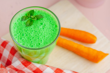 Green smoothie in glass over rustic wooden background