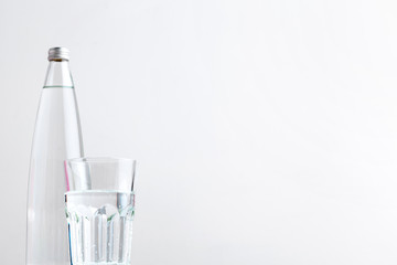 Glass of water with a bottle on table