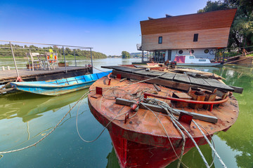Fototapeta na wymiar Metal fishing boat, wooden piers, ducks, and floating hostels on Sava River, Belgrade / Serbia.