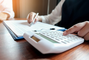 Fototapeta premium Businessman analyzing investment charts and pressing calculator buttons over documents. Accounting Concept.
