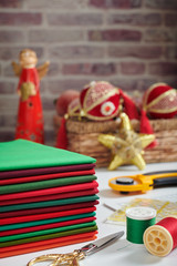 Stack of red and green fabrics, sewing and quilting accessories on Christmas decorations background