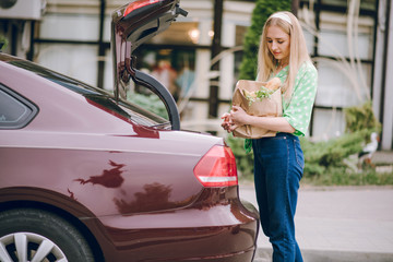 Beautiful blonde girl holds package with food in her hands. Beautiful blonde drinking coffee.