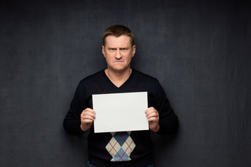Portrait of enraged man holding white blank paper sheet