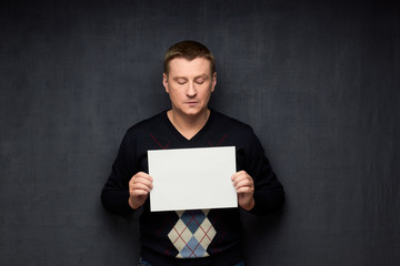 Naklejka premium Portrait of man holding white blank paper sheet