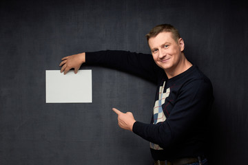 Portrait of happy man holding paper sheet and pointing at it