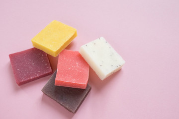 Multi-colored pieces of natural handmade organic soap on pink with place for text. Concept of hygiene, medicine, health care