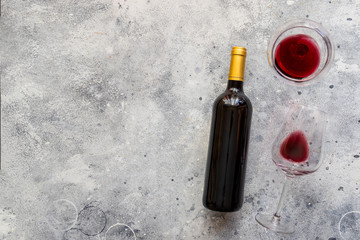 Red wine bottle with red wine glass  on concrete background. Top view Copy space.
