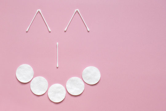 Flatlay white cotton buds and pads on pink with place for text. Face with a smile. Hygiene, medicine, health care, beauty concept © Irina Kulikova