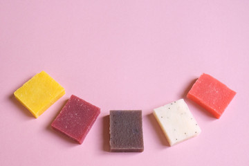 Multi-colored pieces of natural handmade organic soap on pink with place for text. Concept of hygiene, medicine, health care