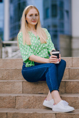 beautiful blonde drinking coffee near the mall