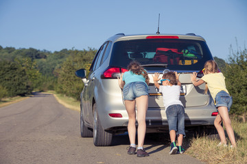 Happy brother and his two sisters are standing near the car at the day time.