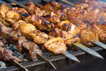 pieces of meat are friend on fire on skewers on grill. close up