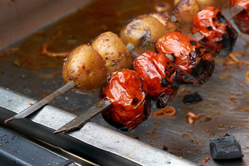 Vegetables on skewers on the grill, vegetarian shish kebab from potatoes and tomatoes