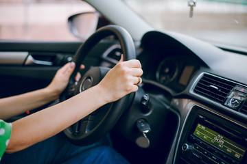 Beautiful blonde girl sitting in the car driving listening to music and drinking coffee