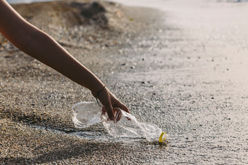 Hand woman picking up plastic bottle cleaning on the beach , volunteer concept