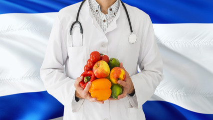 Doctor is holding fruits and vegetables in hands with Israel flag background. National healthcare concept, medical theme.