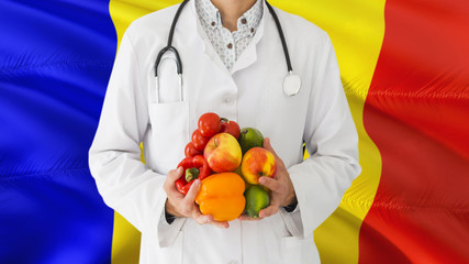 Doctor is holding fruits and vegetables in hands with Moldova flag background. National healthcare concept, medical theme.