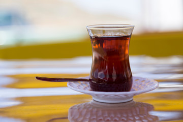 the dark red color glass of tea on the wooden background.